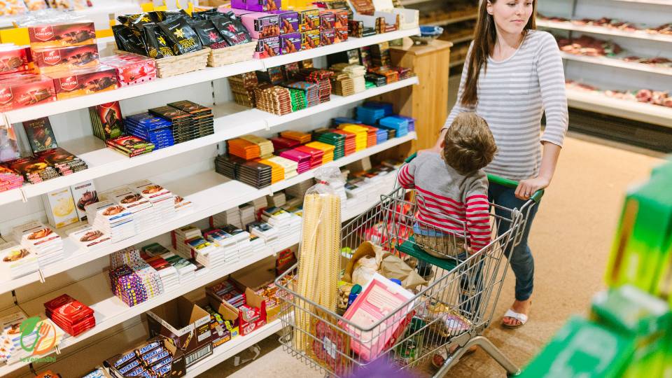 Woman shopping in supermarket or grocery store with kid